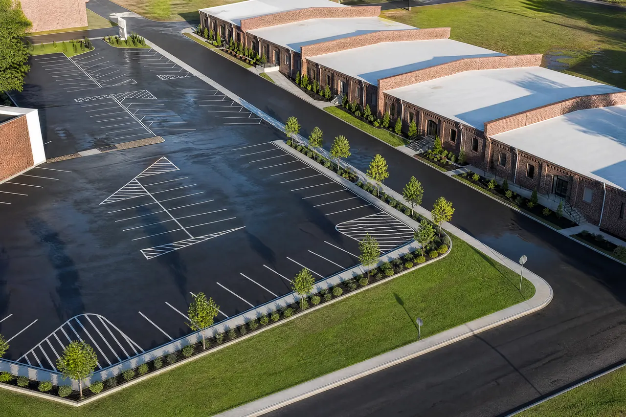 Aerial view of The 680 Block — brick buildings, landscaped drive and a large private parking lot.