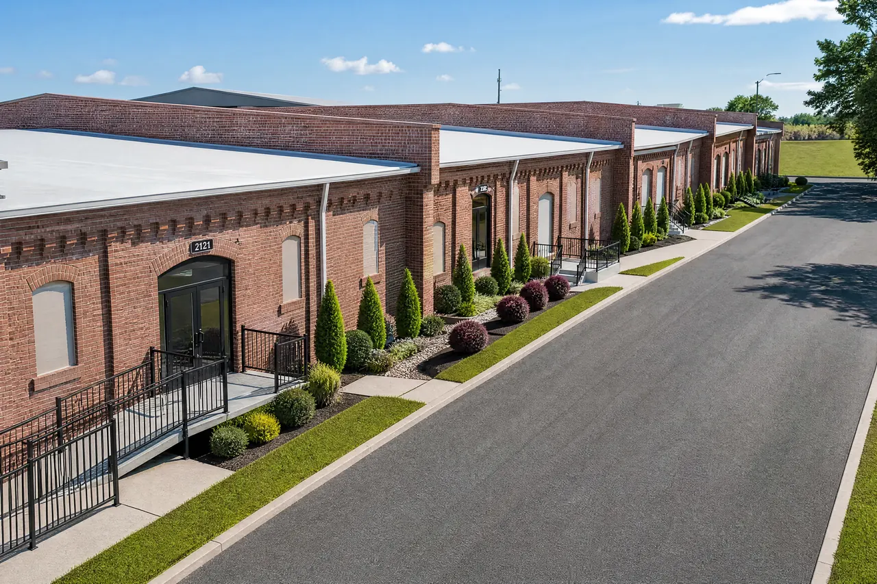 The 680 Block exterior — a long historic brick building with arched windows, iron railings and fresh landscaping along a private drive.