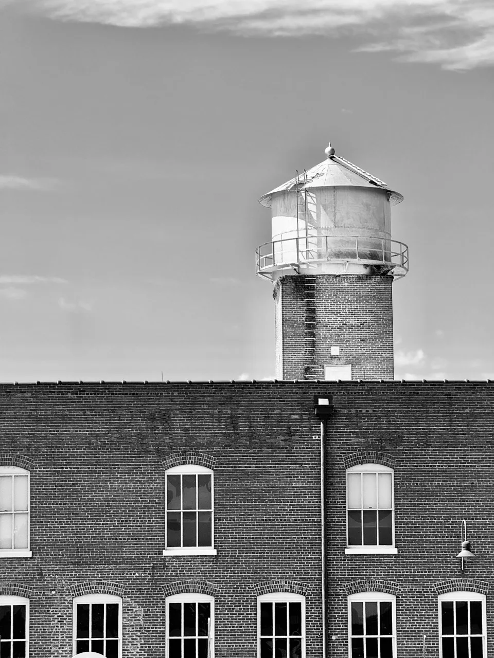 Black-and-white view of a Danville brick mill facade with a rooftop water tower.