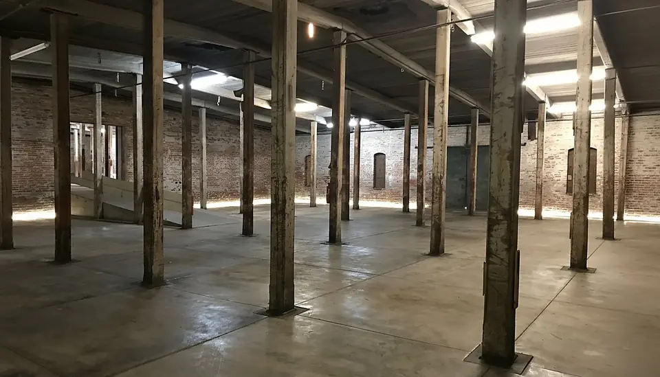 Open warehouse floor in Suites G–H — brick walls, timber columns and concrete.